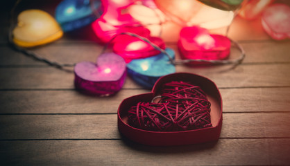 Obraz na płótnie Canvas beautiful colorful heart shaped garland and toy in opened heart shaped box on the wonderful brown wooden background