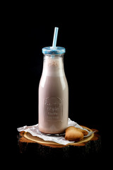 Coffee and soft drink milk in  jar with  high tube and sweets on  napkin on  board on  black...