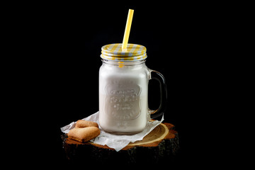 Coffee and soft drink milk in  jar mug with  straw and sweets on  napkin on  board on  black...