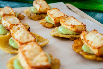Cheese and avocado tostones, plantain crushed in small portions. In the top a fried cheese. - 138504834