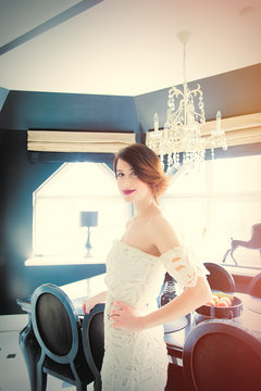 beautiful young woman standing near the table in the light luxury room