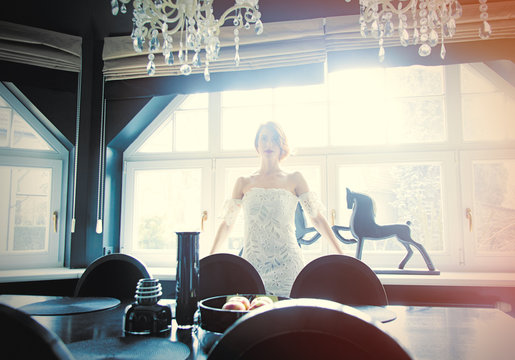 beautiful young woman standing near the table in the light luxury room