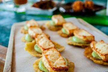 Cheese and avocado tostones, plantain crushed in small portions. In the top a fried cheese. - 138506049