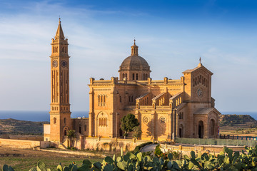 Gozo, Malta - The Basilica of the National Shrine of the Blessed Virgin of Ta' Pinu at sunset with clear blue sky on a summer day - obrazy, fototapety, plakaty