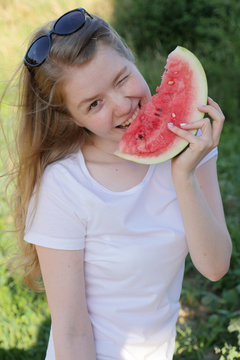 Happy young woman holding watermelon. Young woman with watermelon on the nature background. Picture of young woman holding a big slice watermelon. Woman holding fresh slice of watermelon . 