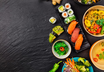 Asian food served on black stone, top view, space for text