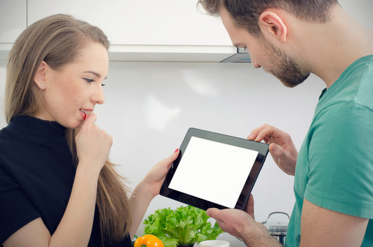 Young people cooking in the kitchen, check top recipes on tablet