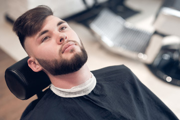 hipsters sitting on a chair in the barbershop. looking to the top