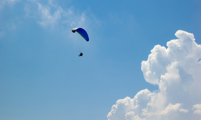 Paraglider flies among the clouds on a sunny day