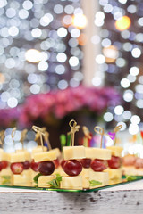 Appetizer of grape, pineapple cubes and cheese are on wooden skewers.