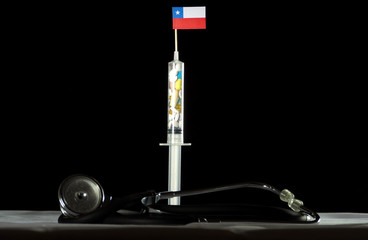 Stethoscope and syringe filled with drugs injecting the Chilean flag on a black background