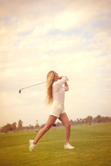 Fashion sport style beautiful woman standing holding golf club on outdoors green field background