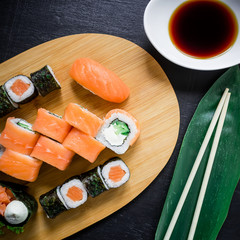 Japanese food - sushi rolls and sauce on a black wood background. Top view. Flat lay