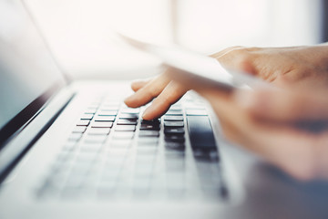 Close-up of young professional businessman sitting at office and using modern laptop and smartphone, Closeup image of female hands typing on laptop keyboard