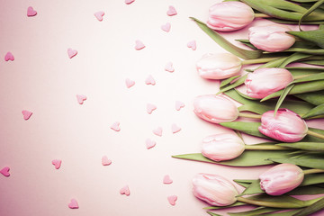 Pink tulips with pink heart sprinkles on the pink background. Flat lay, top view. Valentines background.