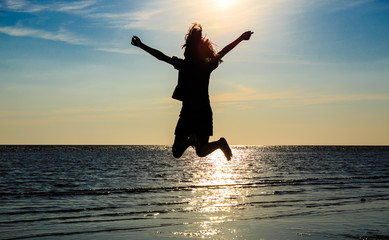 Girl jumping on the beach with the sun.