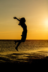 Girl jumping on the beach with the sun.
