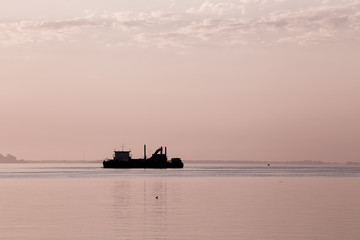 Obraz premium Cargo ship in the sea at dawn