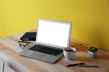 Workplace with laptop against yellow wall background
