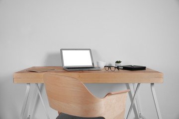 Workplace with laptop against white wall background