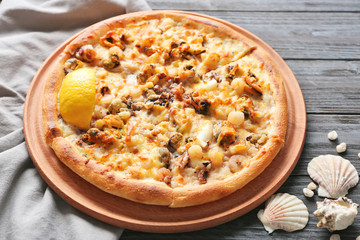 Delicious seafood pizza and shells on grey wooden background