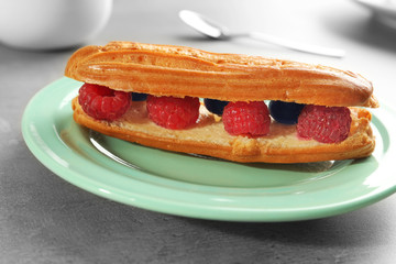 Delicious eclair with berries on green plate