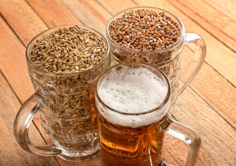 Glasses with fresh beer, wheat and barley on wooden background