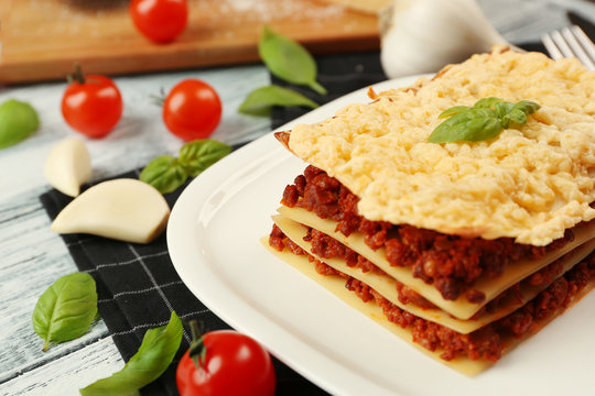 Plate with tasty lasagna on white wooden background