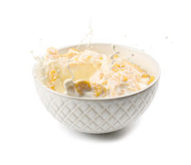 Corn flakes in bowl with milk splash on white background
