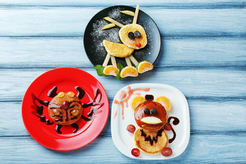 Plates with creative homemade pancakes on wooden table