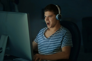 Teenager playing computer game at home late in evening