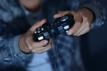 Teenager playing videogame at home late in evening, closeup