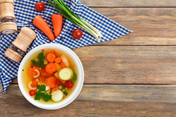 Bowl with vegetable soup on wooden table