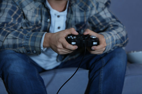 Teenager playing videogame at home late in evening, closeup