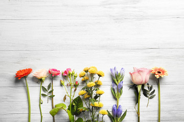 Beautiful fresh flowers on white wooden background