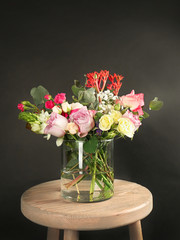 Glass vase with beautiful bouquet of fresh flowers on black background