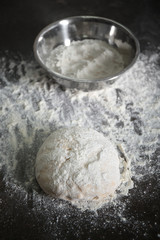Fresh dough and metal bowl on kitchen table