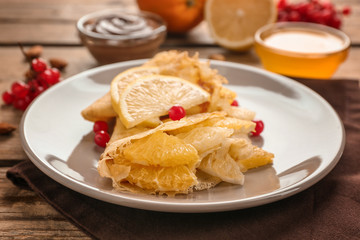 Tasty pancakes with citrus fruits on wooden table