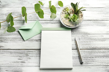 Blank notepad and succulents on wooden background