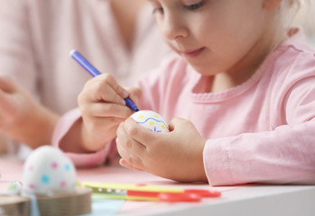 Mother and little girl decorating Easter eggs