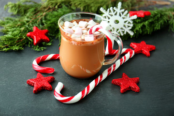 Christmas composition with candy canes, cup of coffee and decorations on grey table