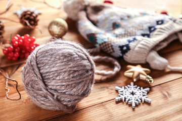 Obraz na płótnie Canvas Yarn ball, knitted hat and Christmas decorations on wooden table
