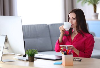 Young beautiful designer drinking coffee in office