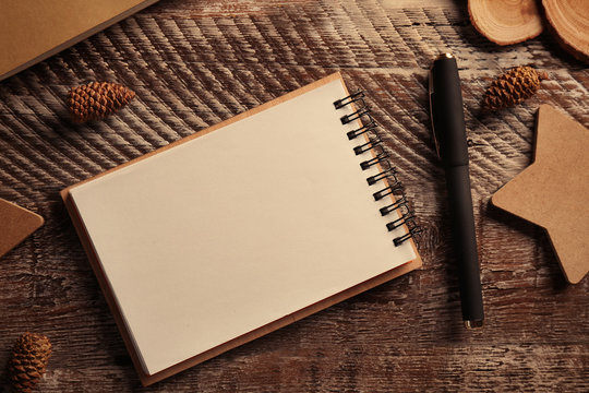 Open notepad and pen on wooden background