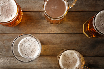 Mugs with beer on wooden background