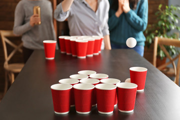 People playing Beer Pong on table at bar