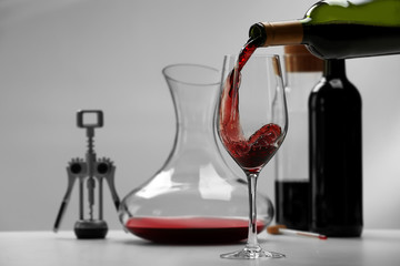 Pouring wine in glass on light background