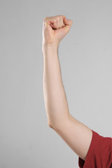Raised male hand with clenched fist on light background