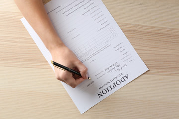 Female hand filling in adoption paternity registry at table