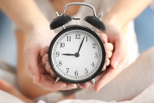 Hands of mother and child with alarm clock, closeup